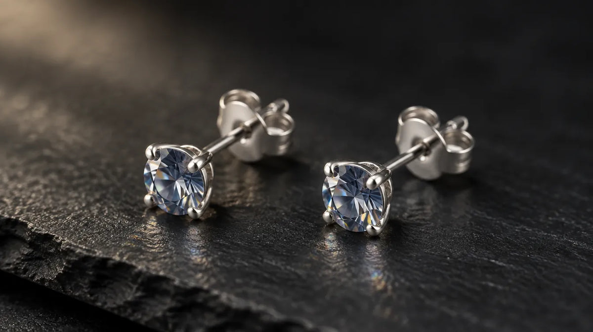 Pair of silver solitaire stud earrings with sparkling stones on slate