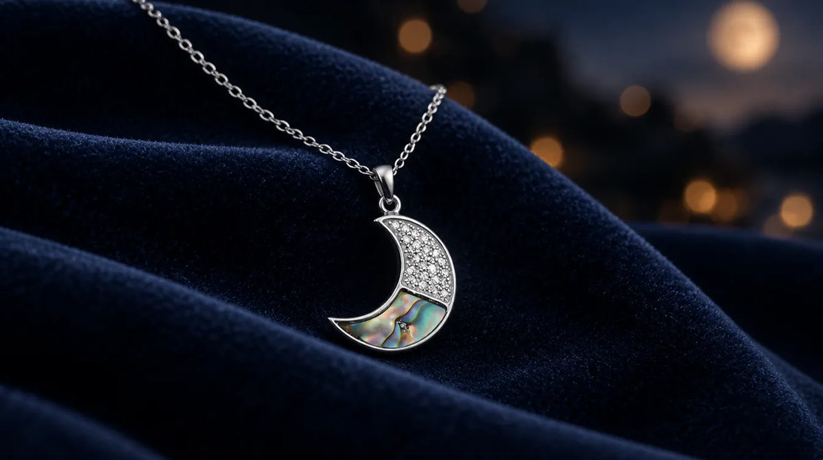 Silver crescent moon pendant on navy velvet with soft evening lights